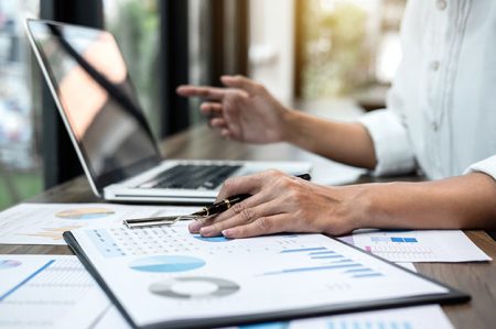 Business woman accountant working audit and calculating expense financial annual financial report balance sheet statement, doing finance making notes on paper checking document.