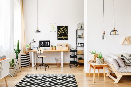 Black and white geometric carpet in multifunctional workspace with artwork on wall above desk